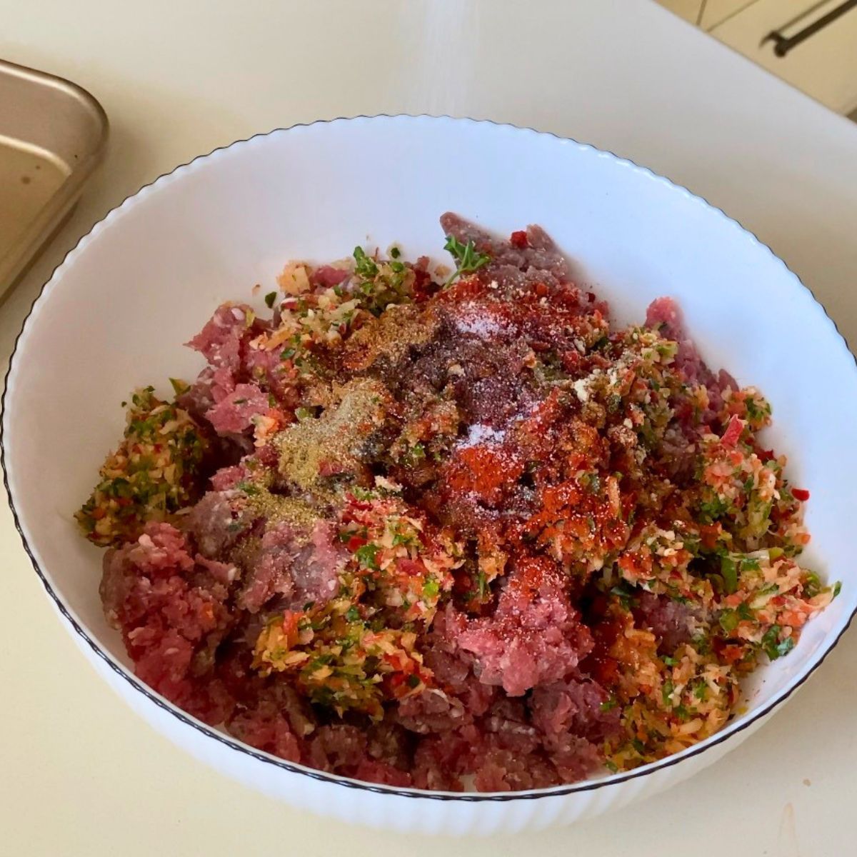 Ground lamb and beef in a bowl with spices for sheet kebabs.