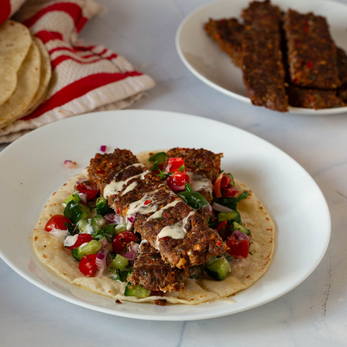 Sheet pan kebabs on a plate over salad and flatbread.