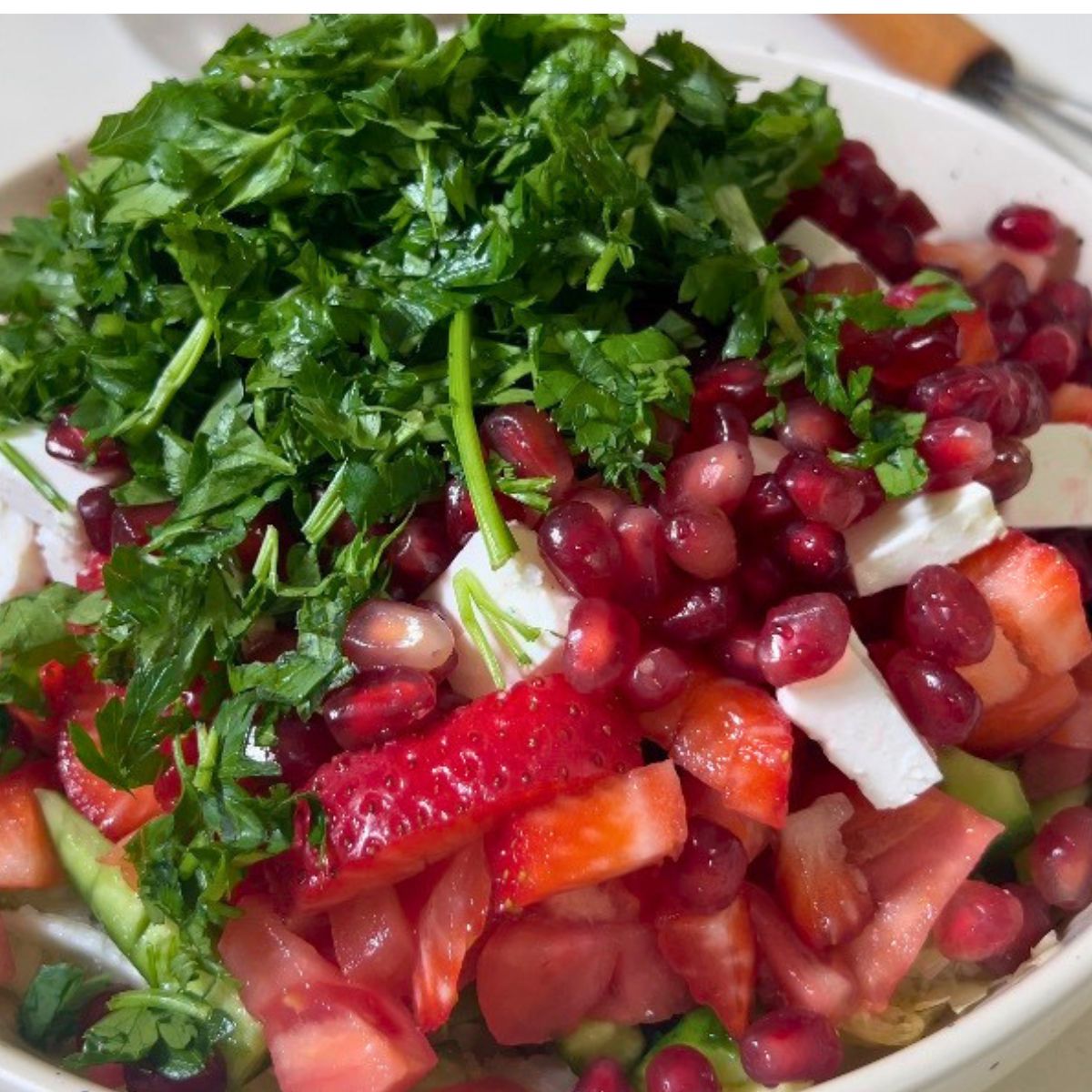 Adding strawberries and veggies into a bowl.