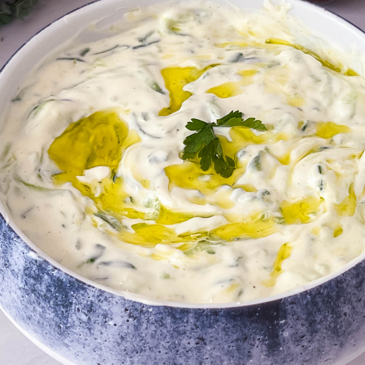 A white bowl with tzatziki sauce.