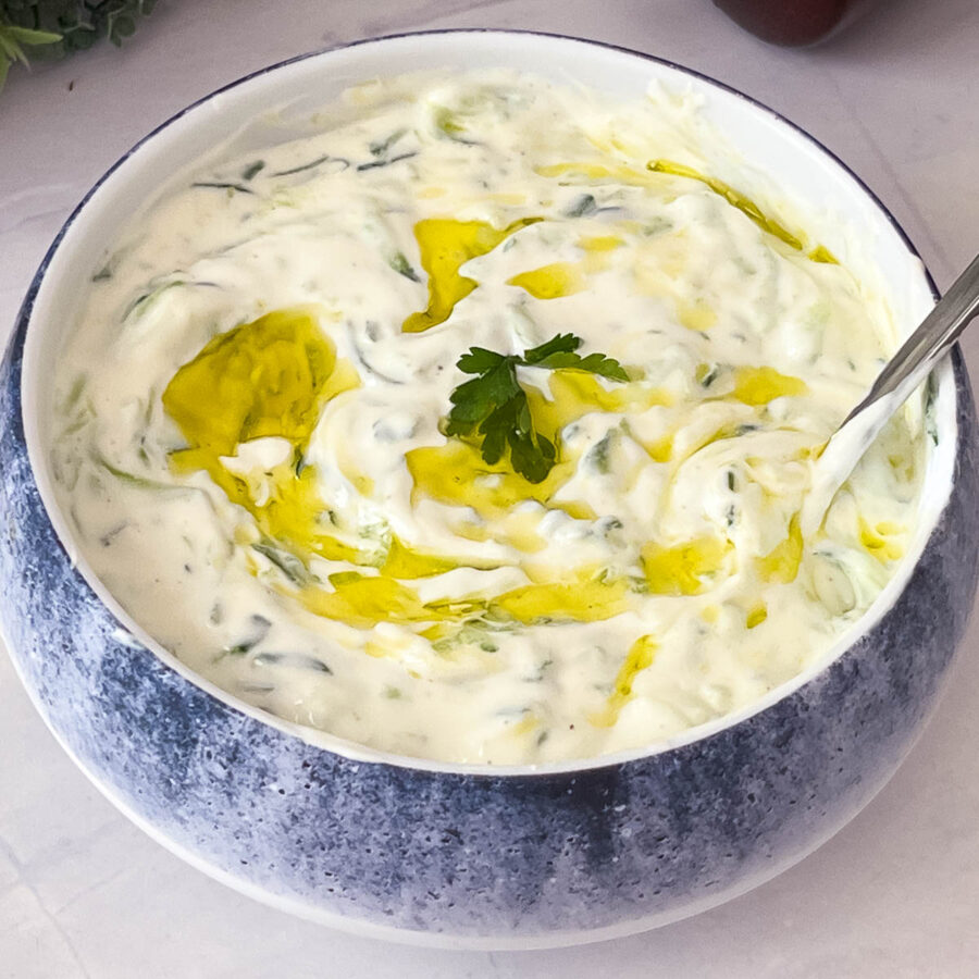 A white bowl with Greek yogurt with Tzatziki Sauce.
