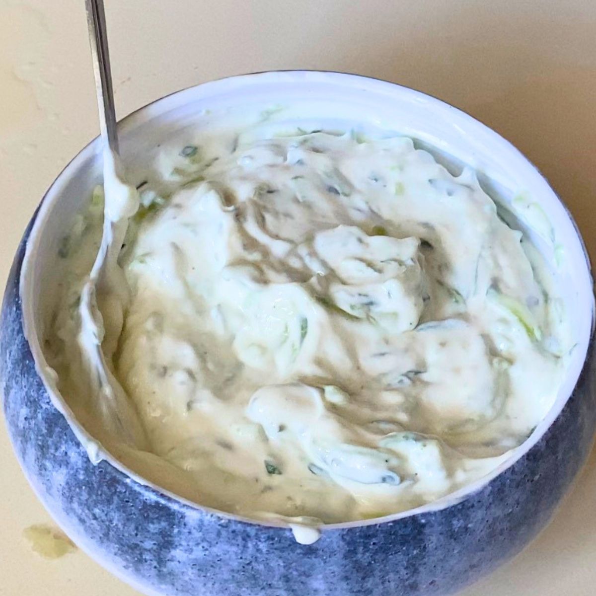 A blue bowl with greek yogurt tzatziki sauce.