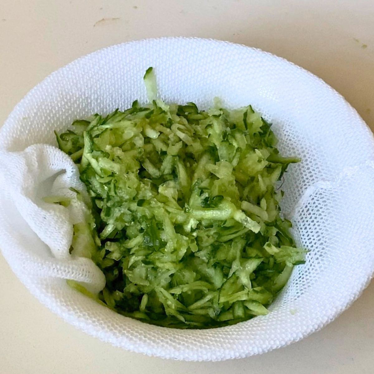 Grated cucumber in a white bowl for tzatziki sauce.