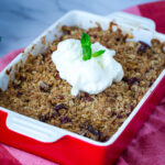 A red baking dish with peach crisp.