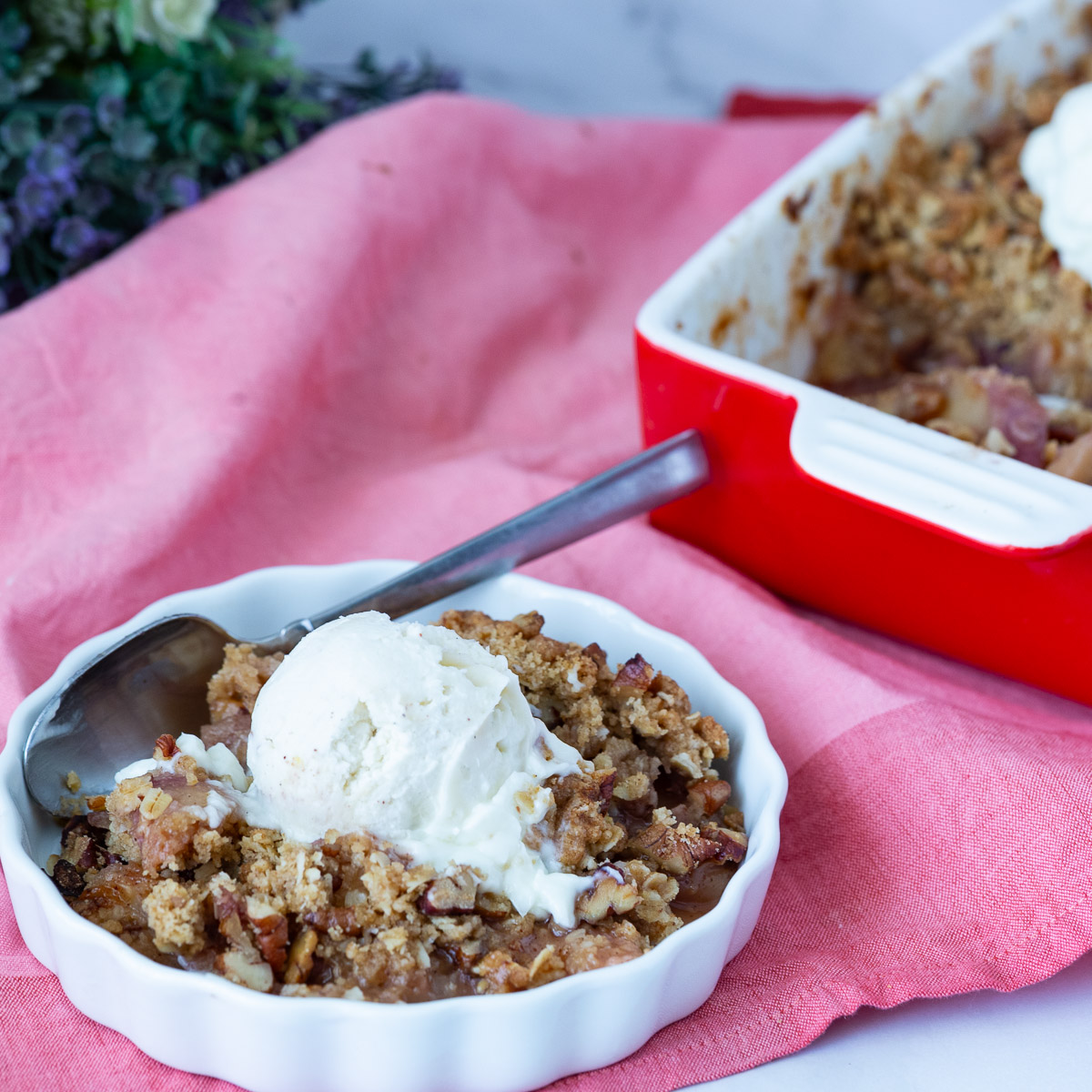 A ramekin with peach crisp and ice cream.