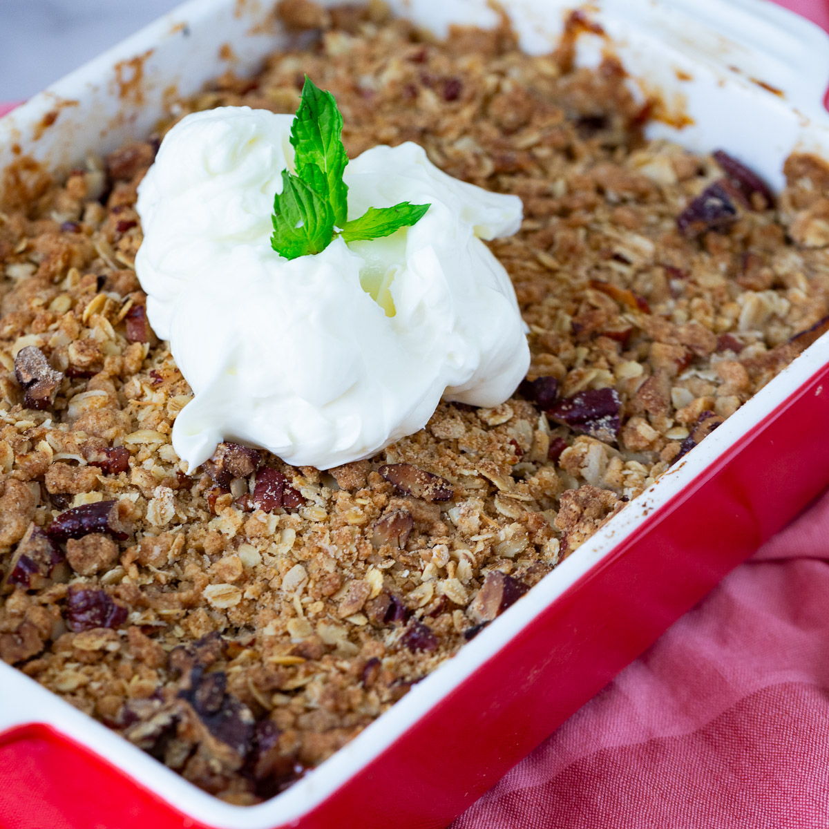 A red baking dish with crisp and fresh peaches.