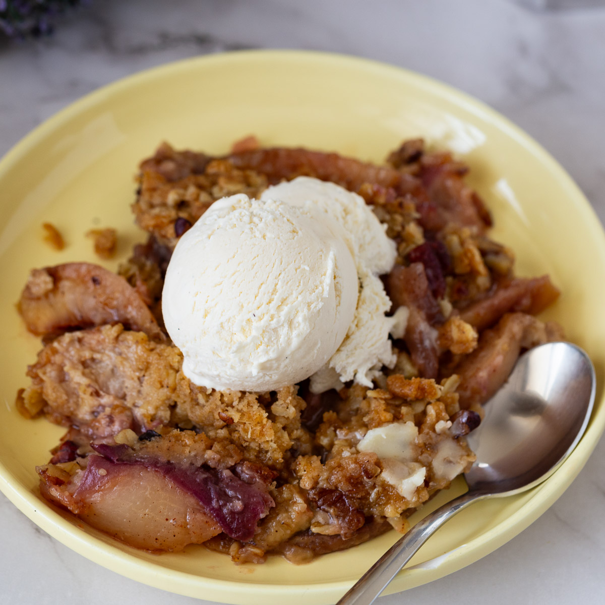 A yellow plate with crisp peaches and ice cream.