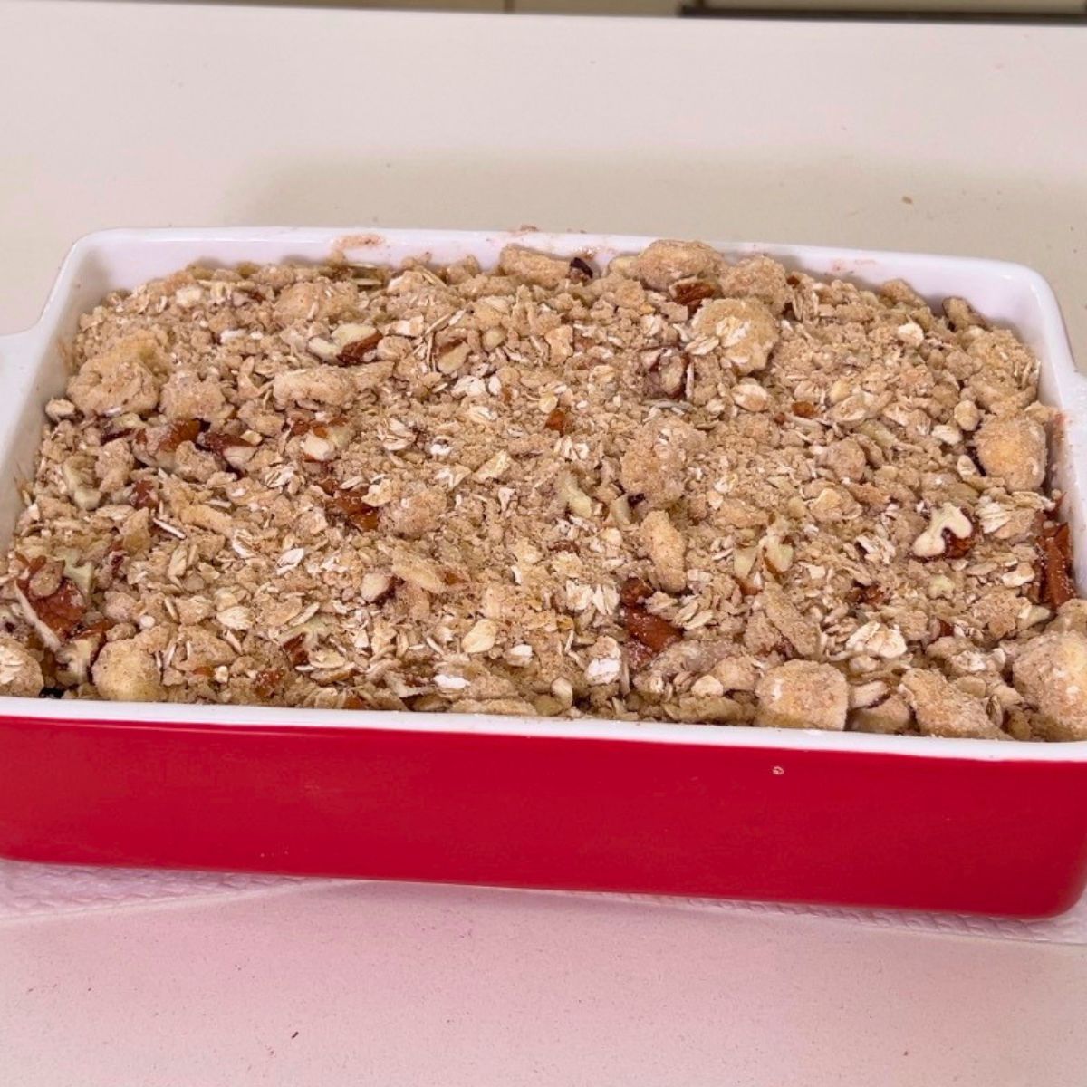 Adding oat streusel over fresh peach filling.