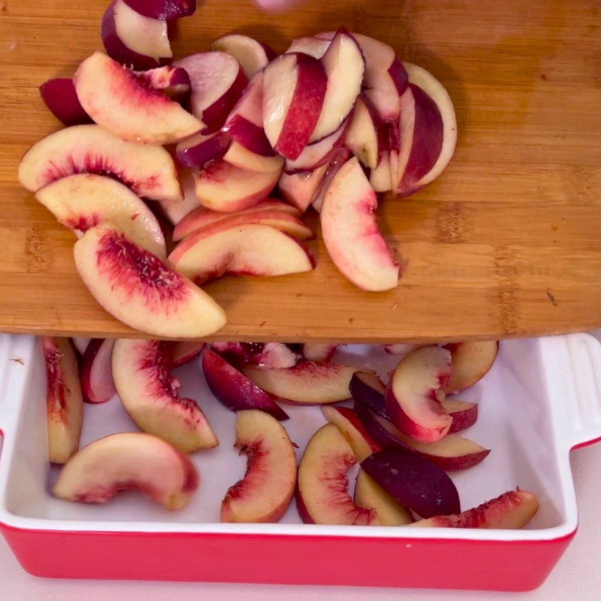 Adding fresh peaches in a baking dish.