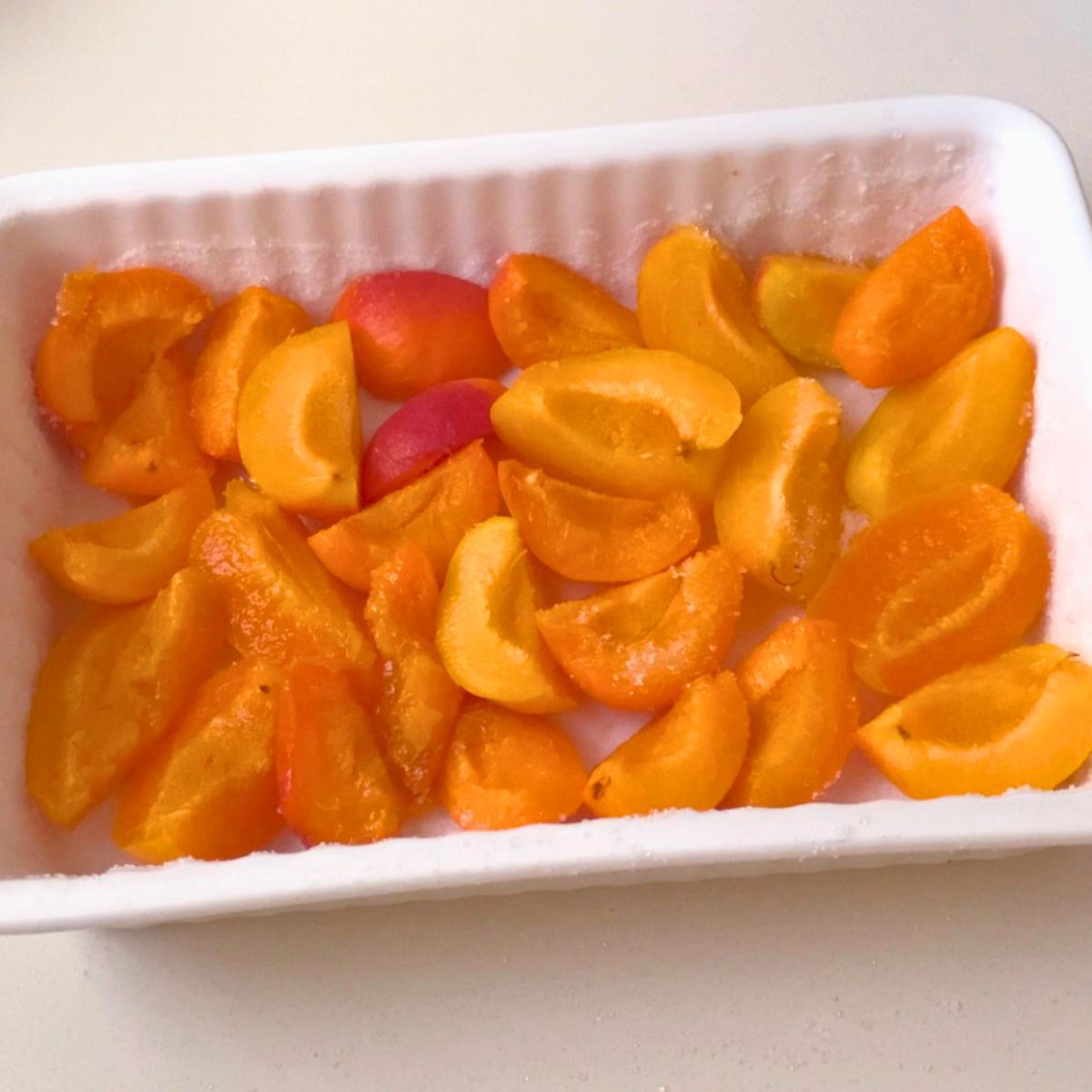 A baking dish with fresh apricot quarters.