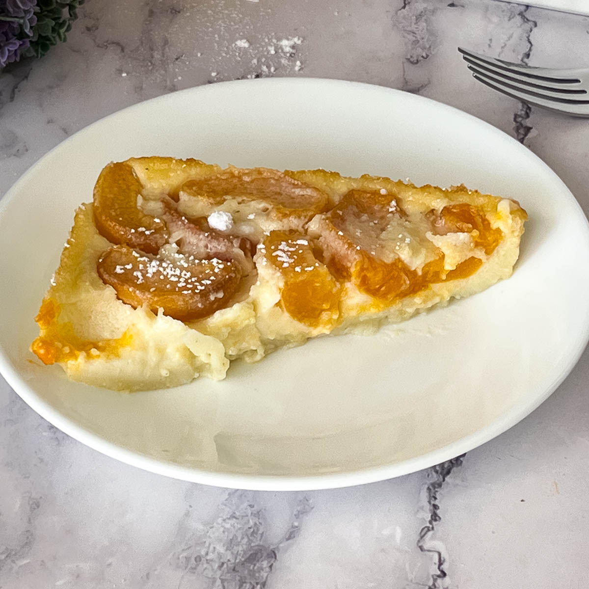 A plate with a slice of apricot clafoutis.