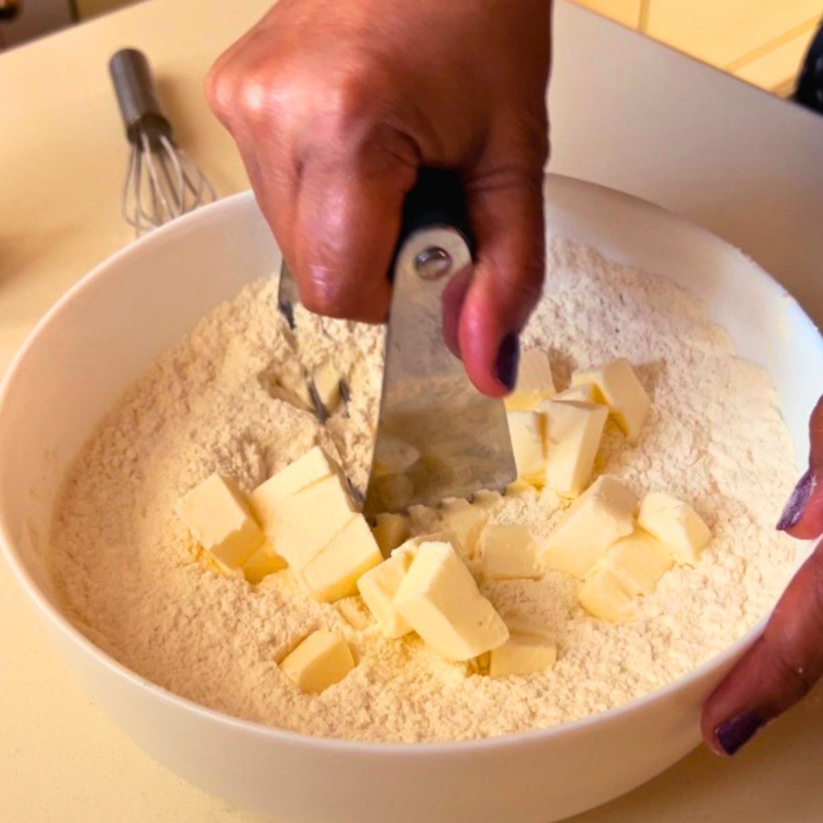 A mixing bowl with dry ingredients and cold butter.