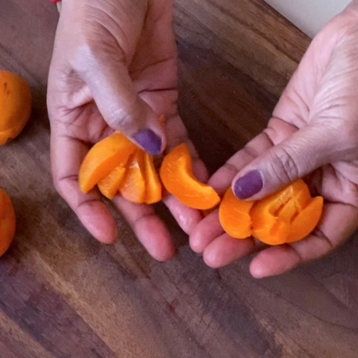 Sliced apricots on a wooden board.