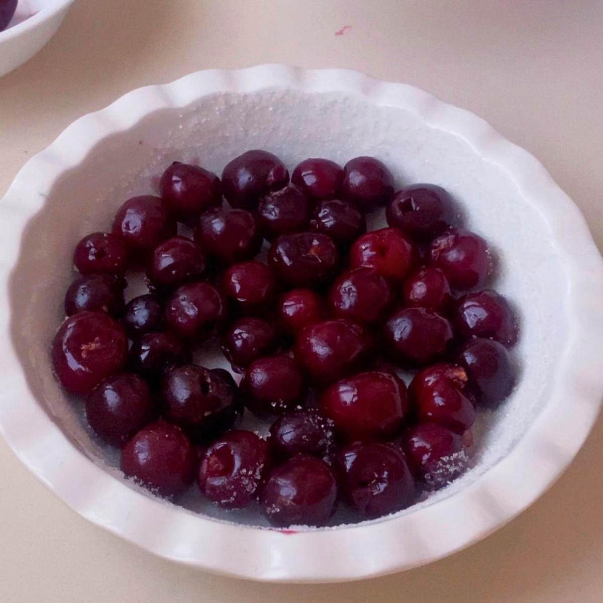 A pie pan with pitted cherries.