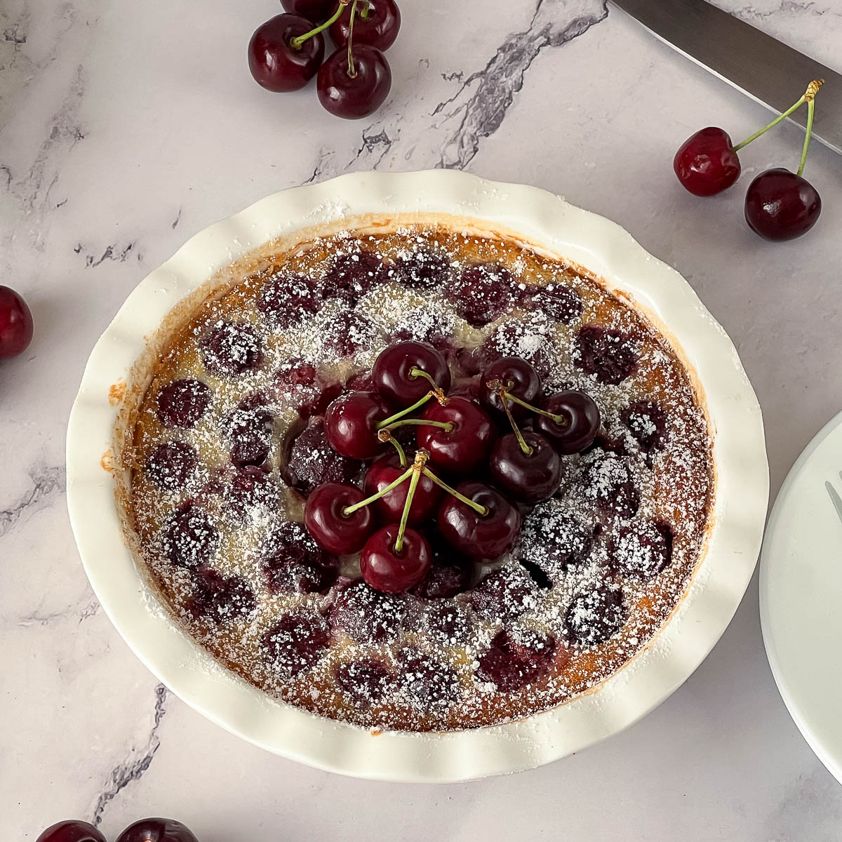 A white pie dish with baked clafoutis.
