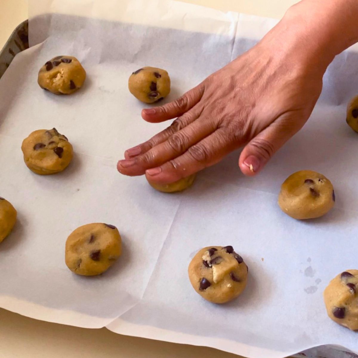 Pressing chocolate chip tahini cookies on the baking tray.