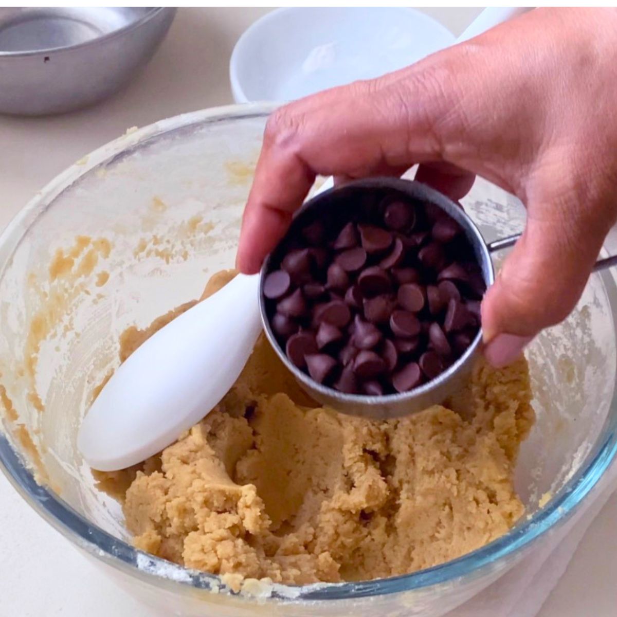 Adding chocolate chips to the tahini cookies dough.
