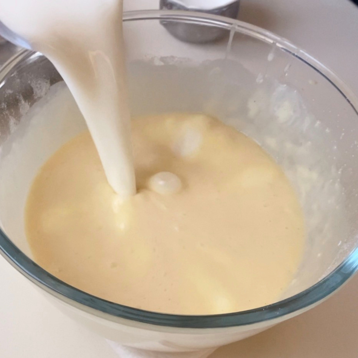 Adding heavy cream to the custard mixture.