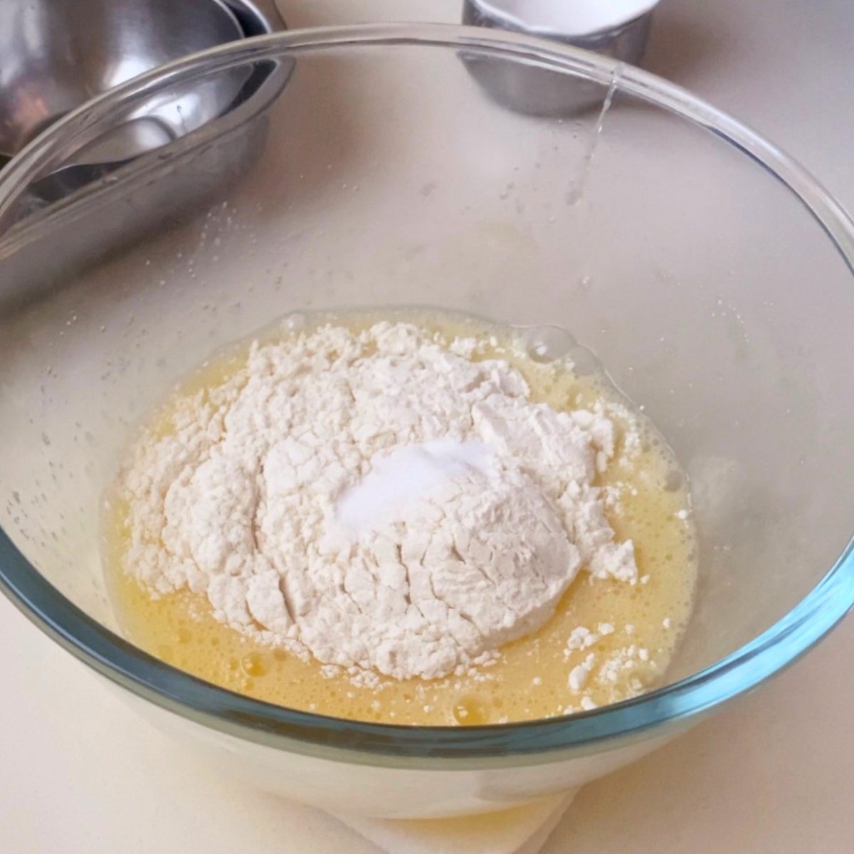 A glass dish with eggs, sugar and flour.