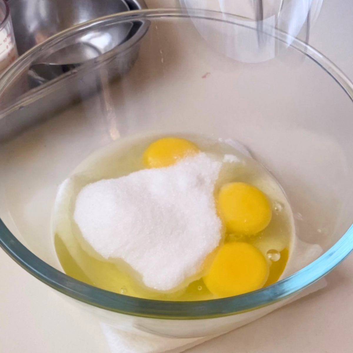A glass dish with eggs, sugar and salt.