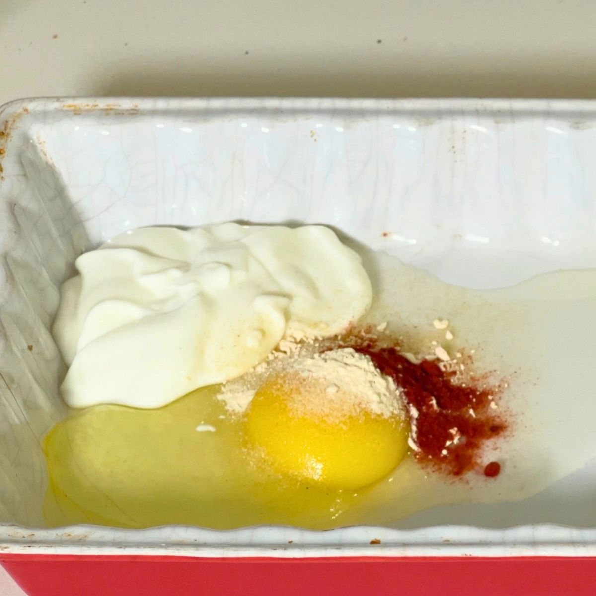 Combining the egg and yogurt mixture for chicken cutlets.