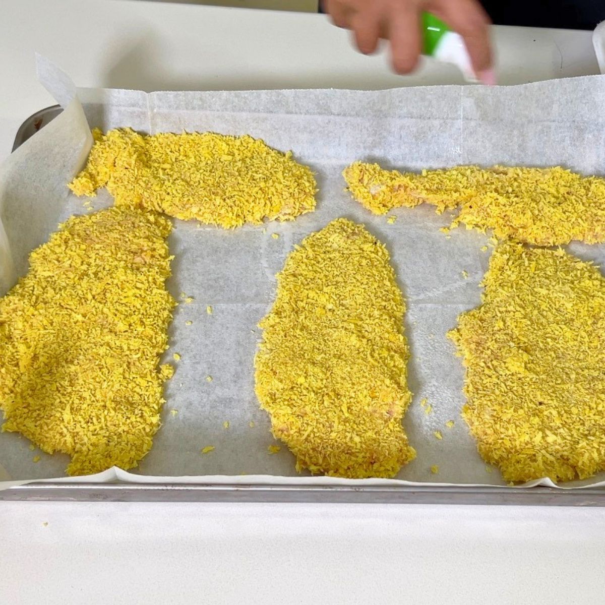 Breaded chicken breast on a baking tray.