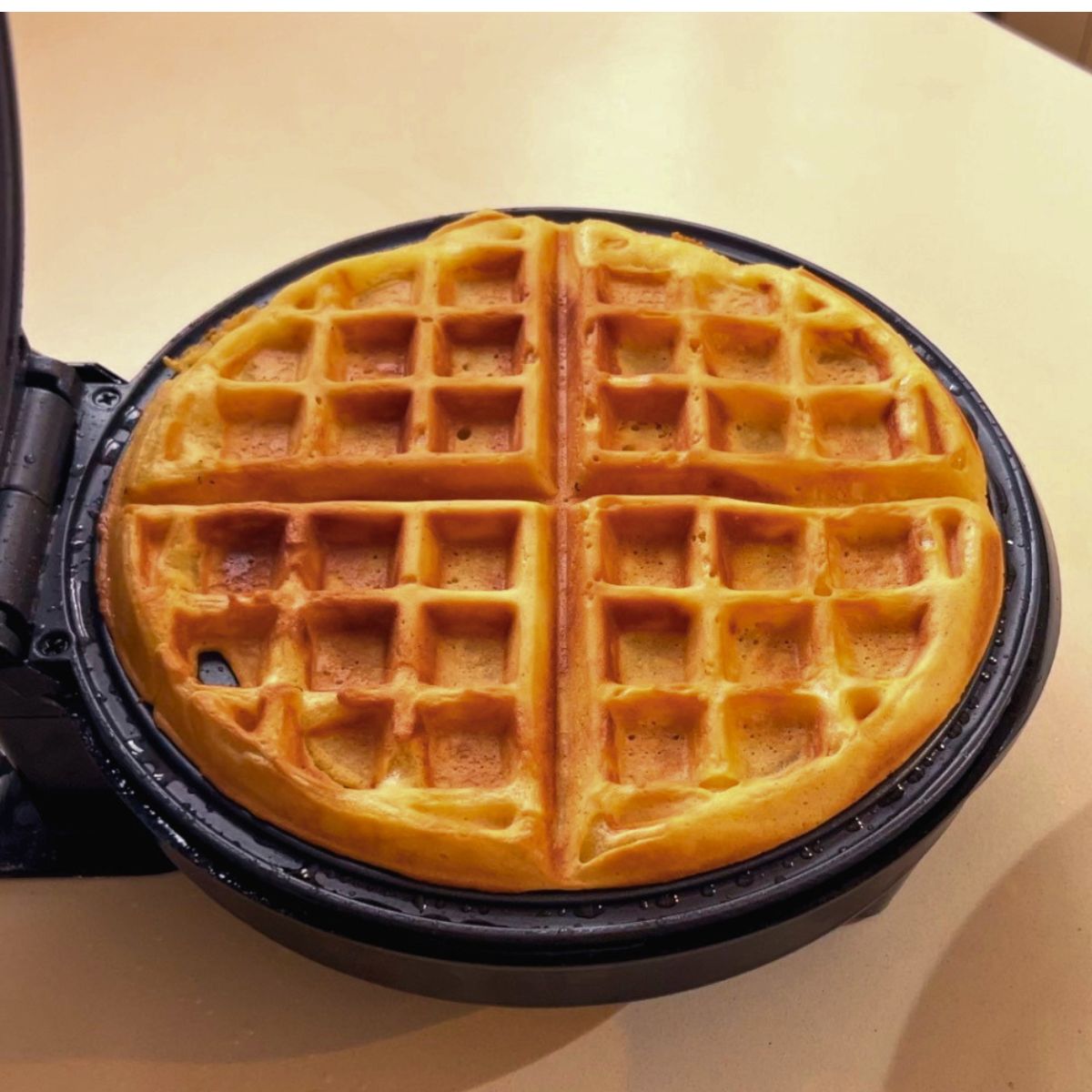 A waffles iron with fresh waffle.