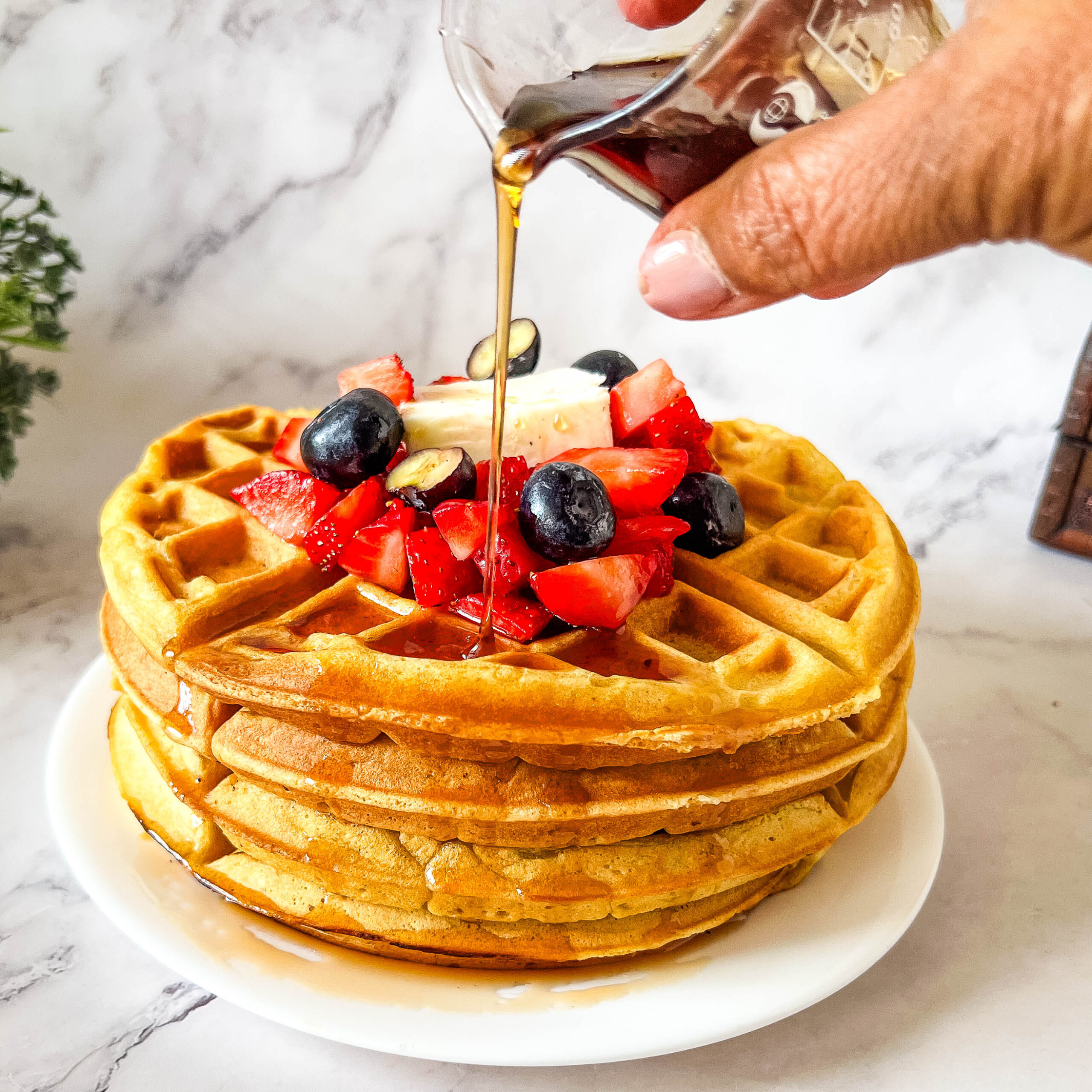 Pouring maple syrup on the waffles.