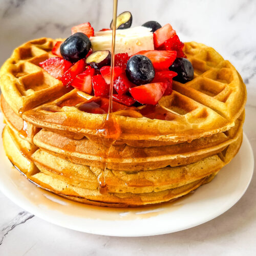 Pouring honey over the waffles with fresh fruits.