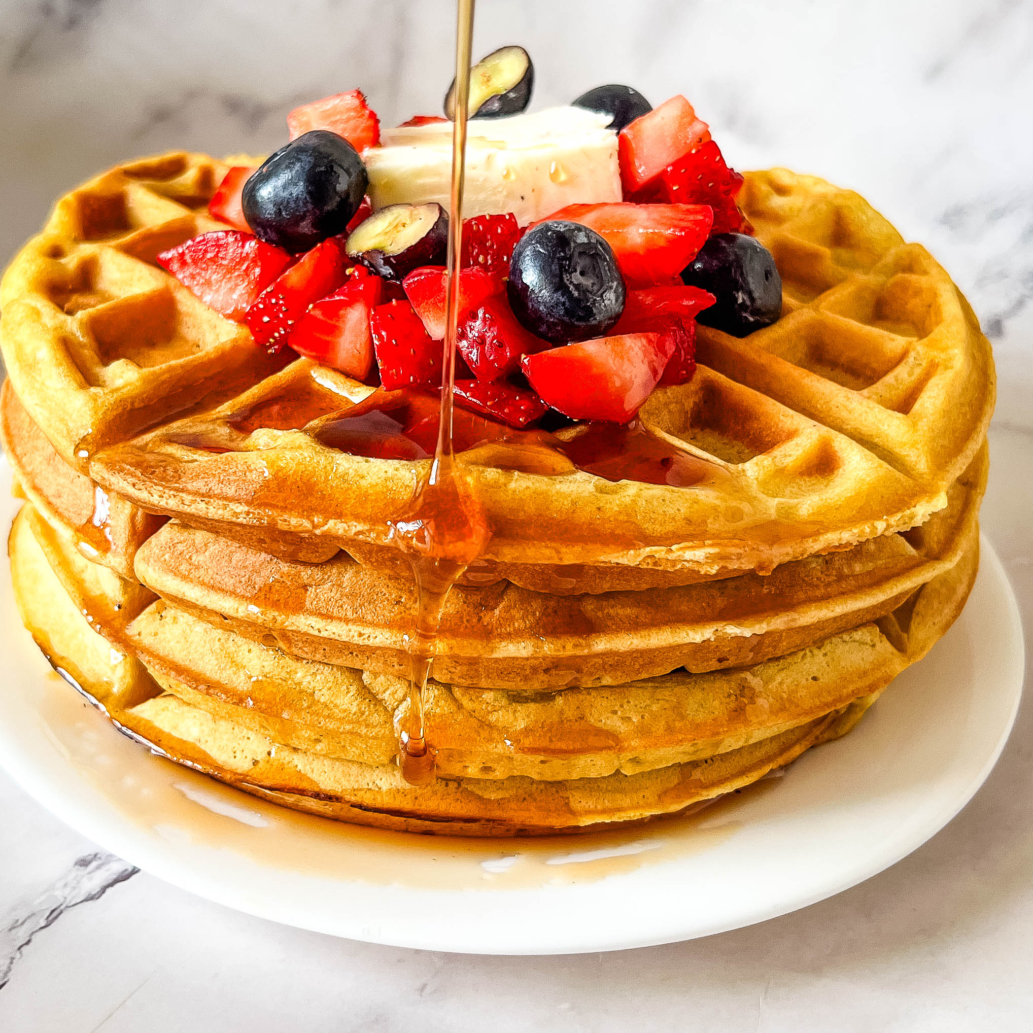 Pouring honey over the waffles with fresh fruits.