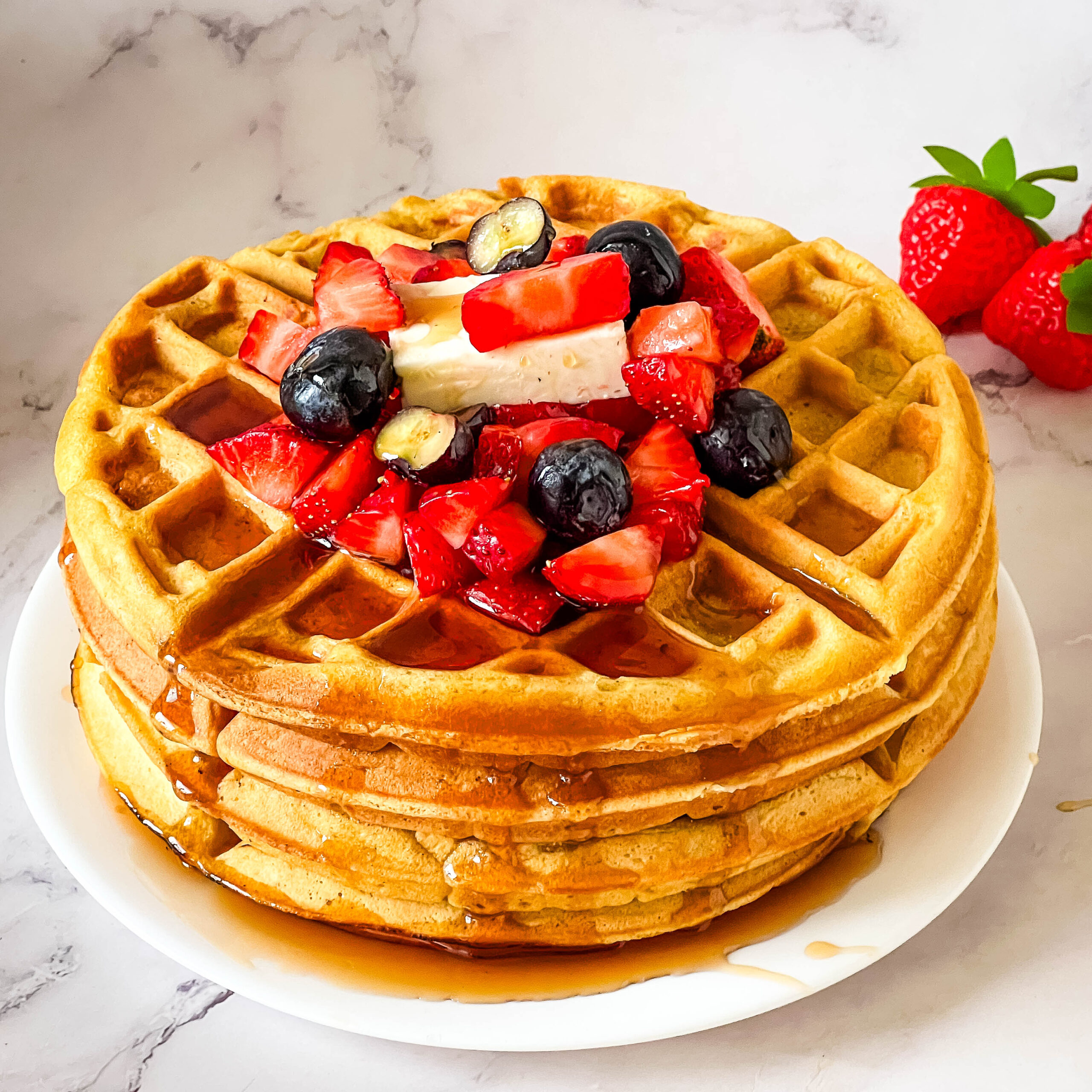 A stack of buttermilk waffles with fresh fruits.