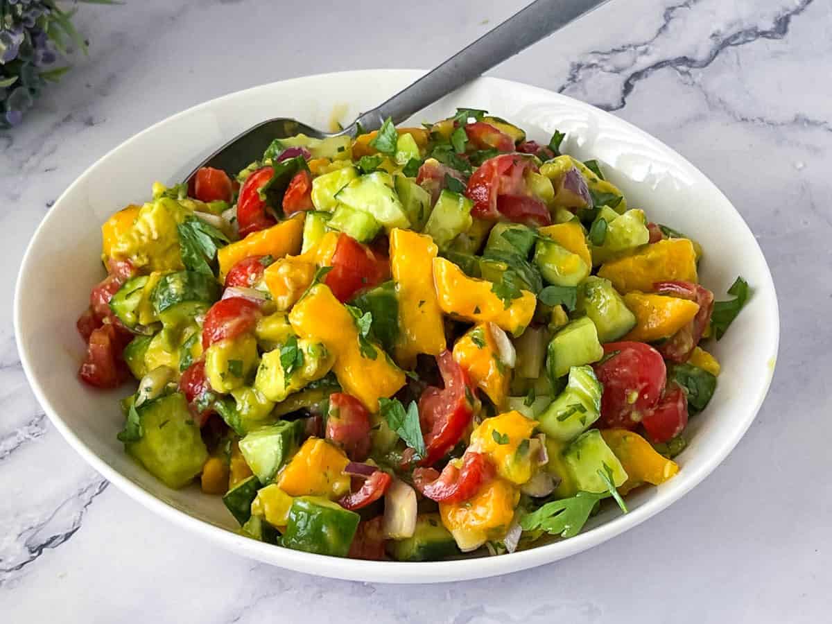 Salad bowl with mango salad and dressing.