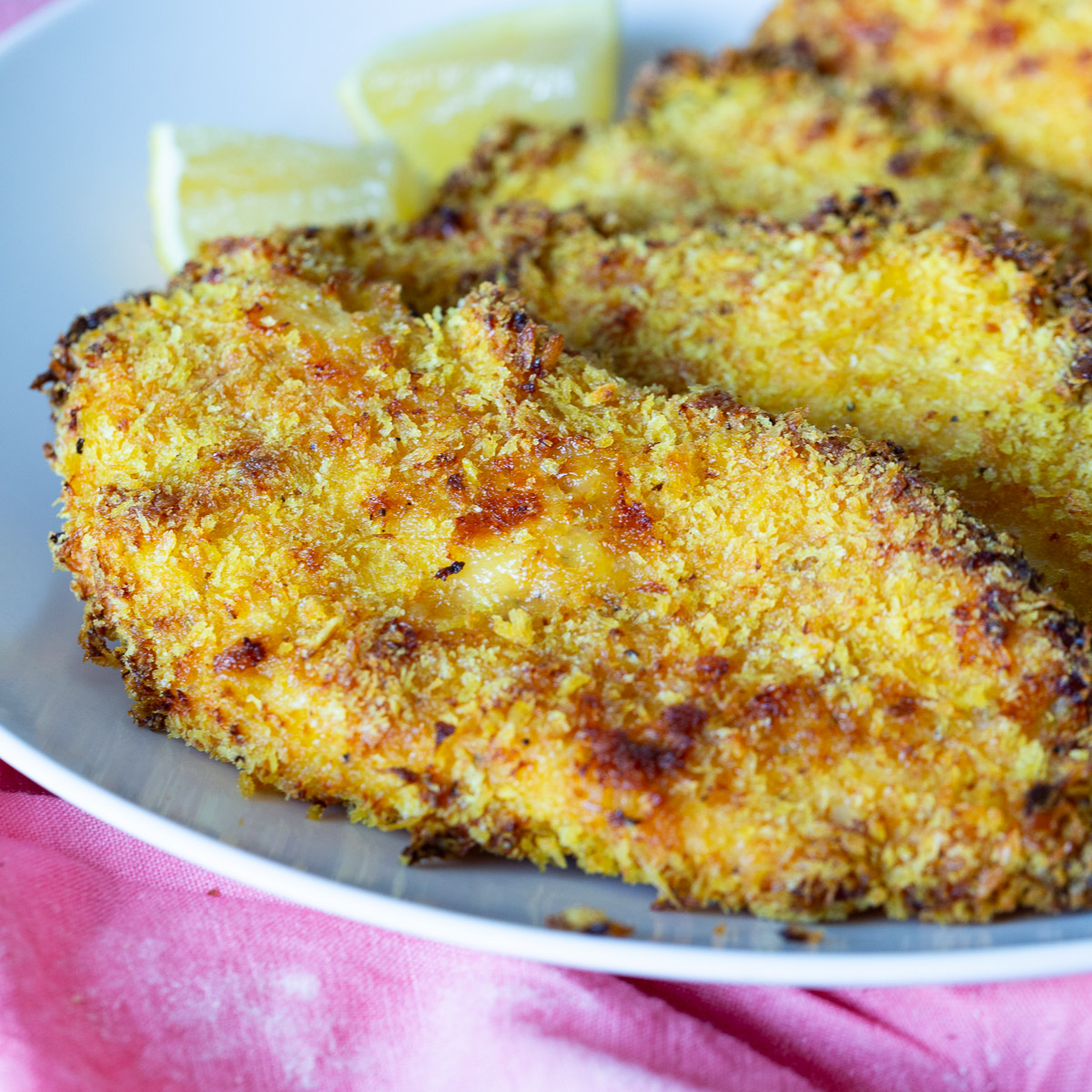 A plate with baked crispy chicken breast.