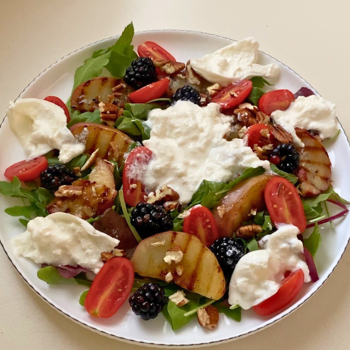 A fresh burrata ball scattered over the peach salad.