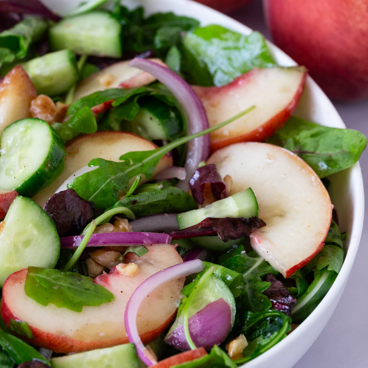 A white plate with fresh peach salad.