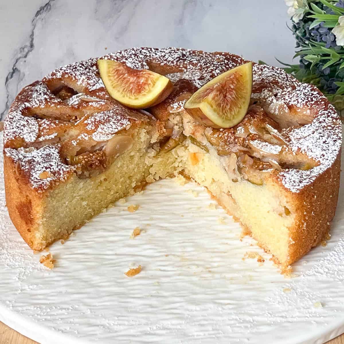 An almond cake with fresh figs on cake stand.
