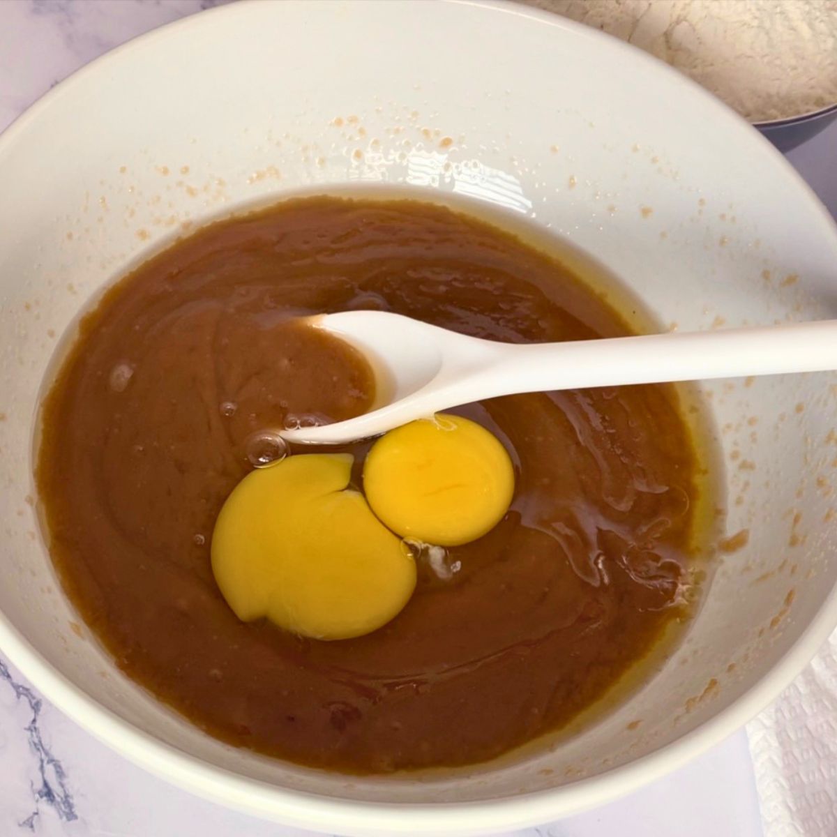 Adding egg and egg yolk to cookie dough.