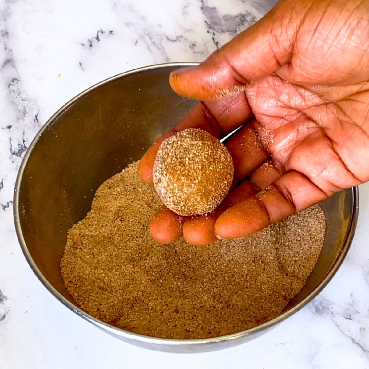 A bowl with cinnamon sugar coating cookie dough.