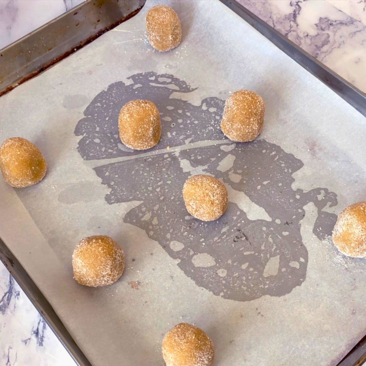 A baking sheet with brown sugar cookie dough balls.