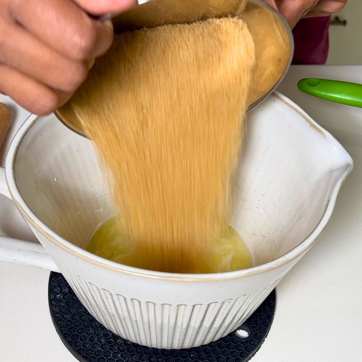Adding sugar to the melted butter for cake batter.