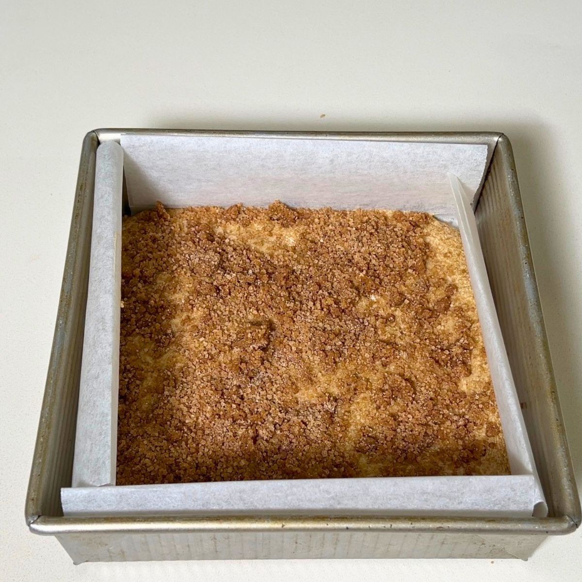 Adding cinnamon streusel topping to the cake.