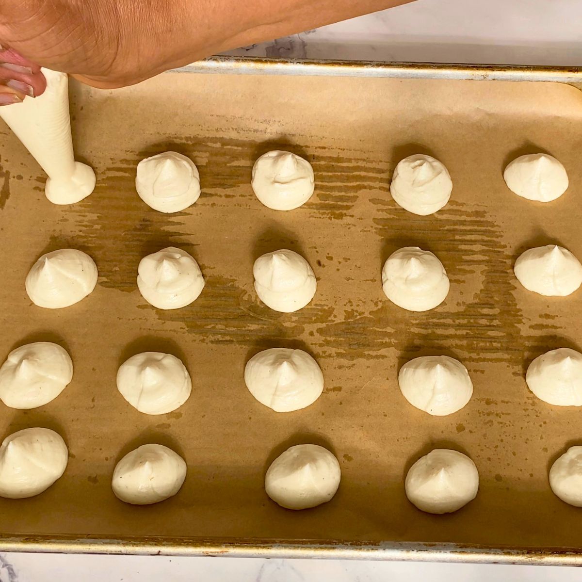 A baking tray with cream cheese piped for stuffing in cookies.