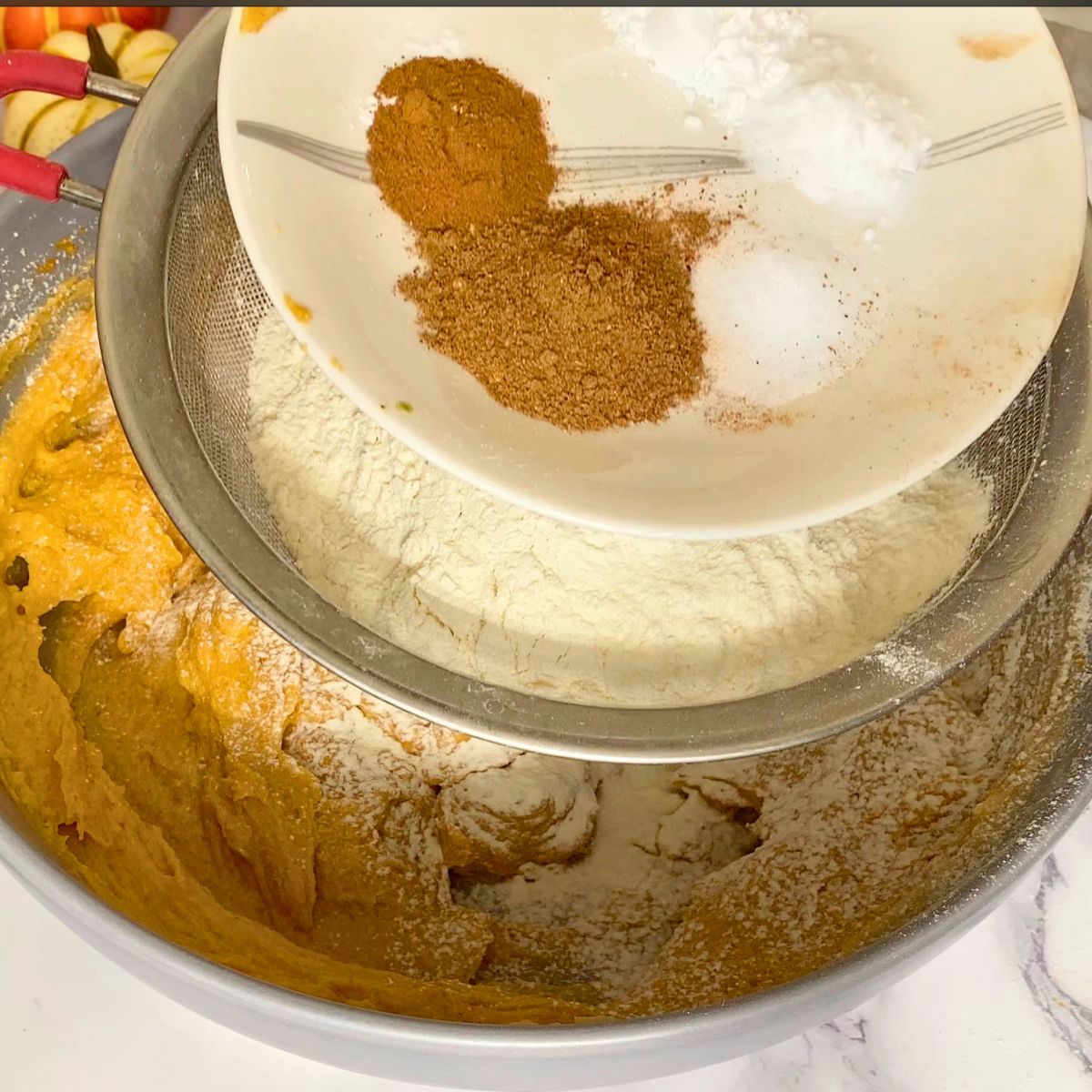 Adding flour spices and leavening to the cookie dough.