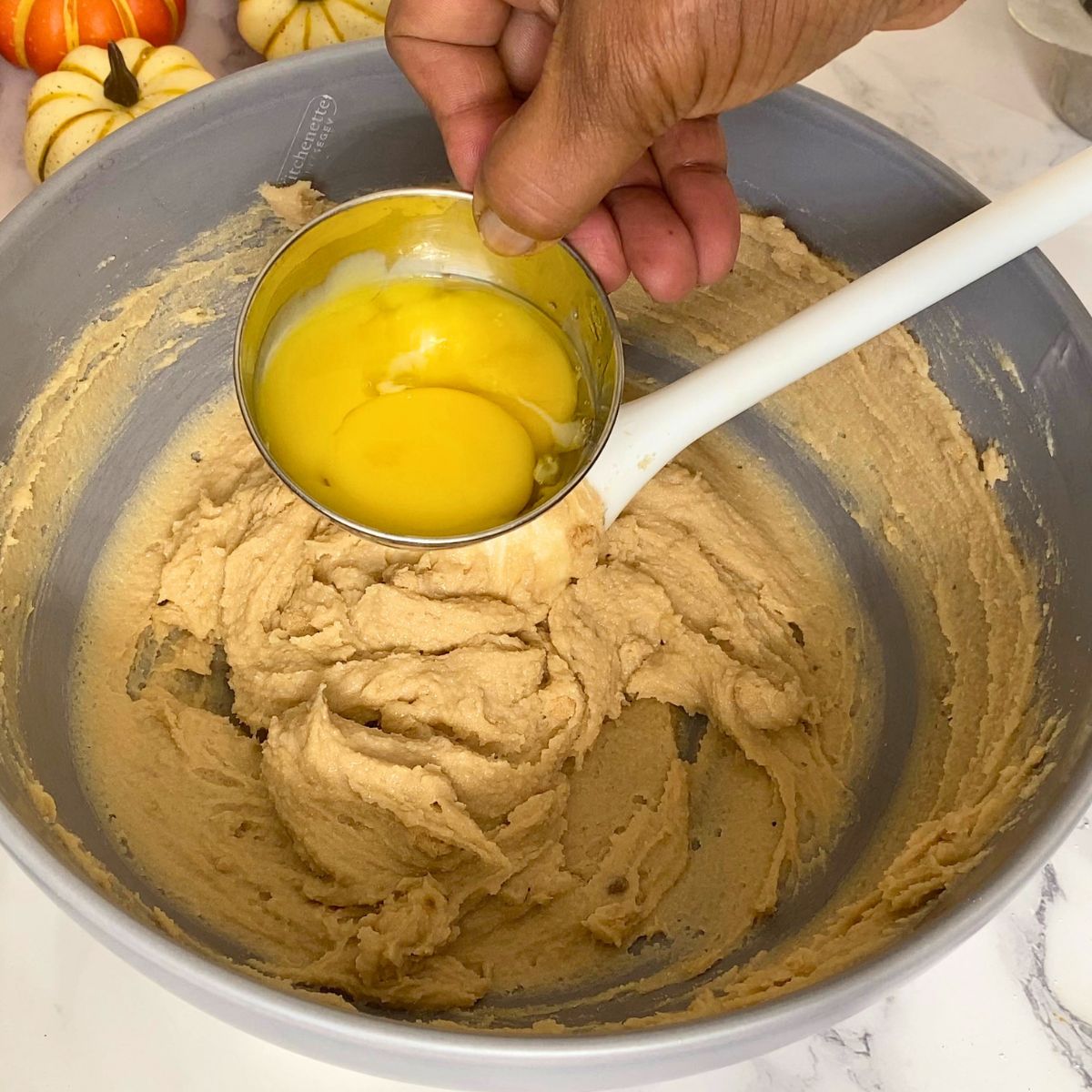 Adding egg yolks to the cookie dough.