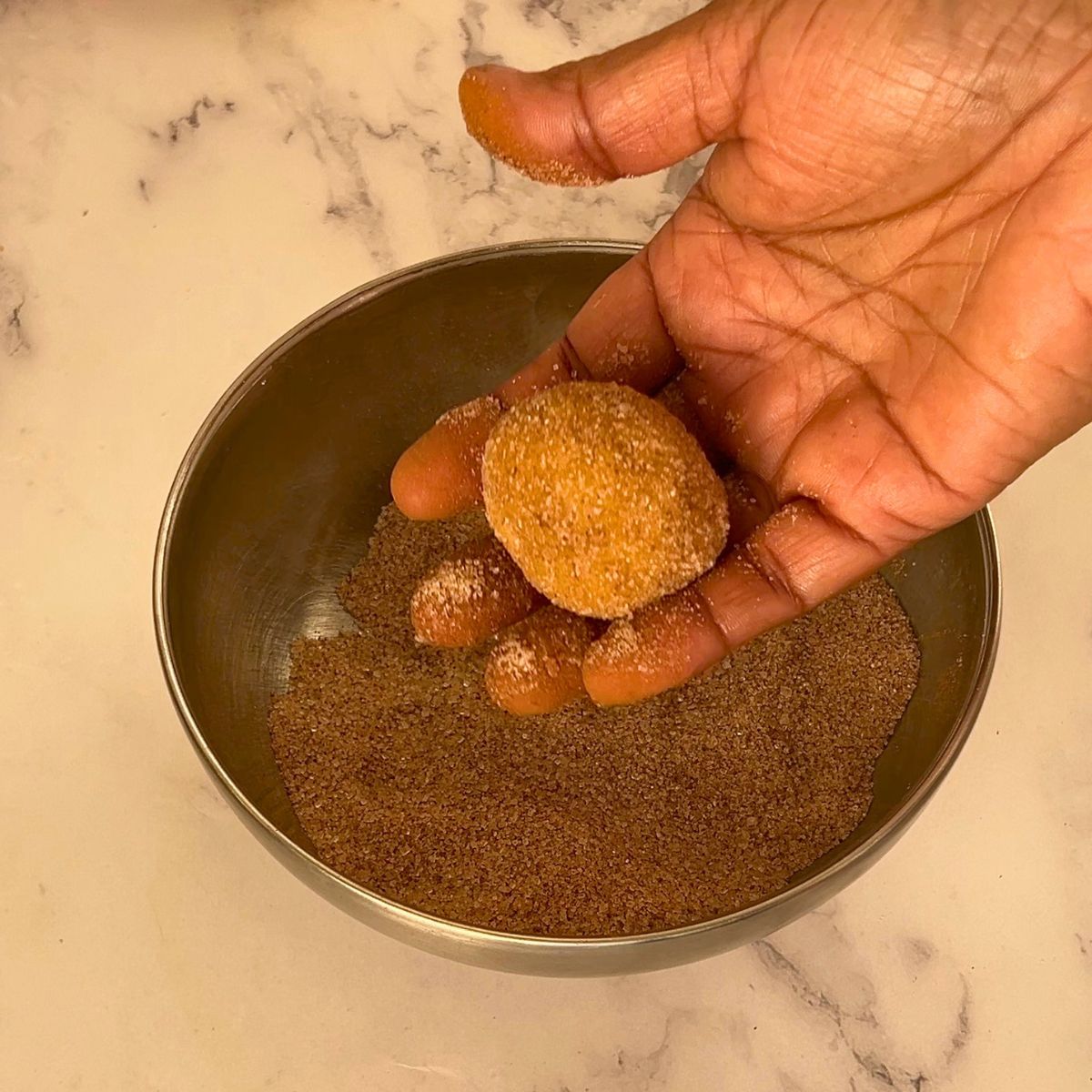Coating the pumpkin cookie dough ball in cinnamon sugar.