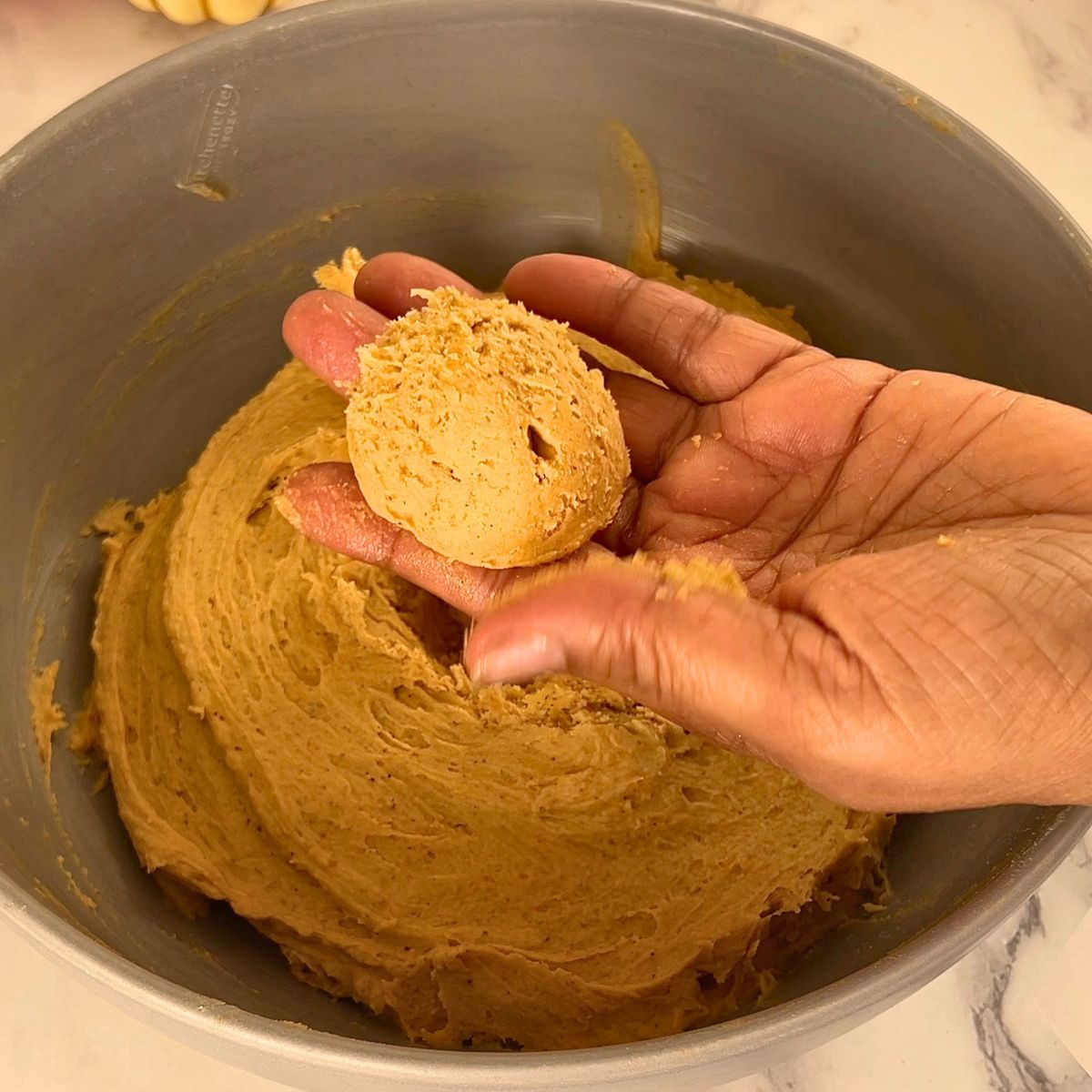 A pumpkin cookie dough into a ball.
