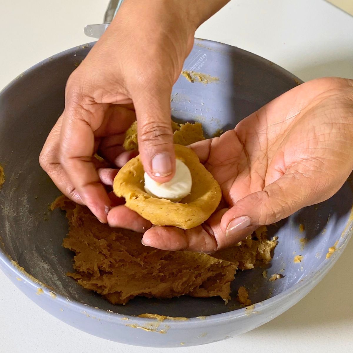 Stuffing the cream cheese inside the pumpkin cookie.