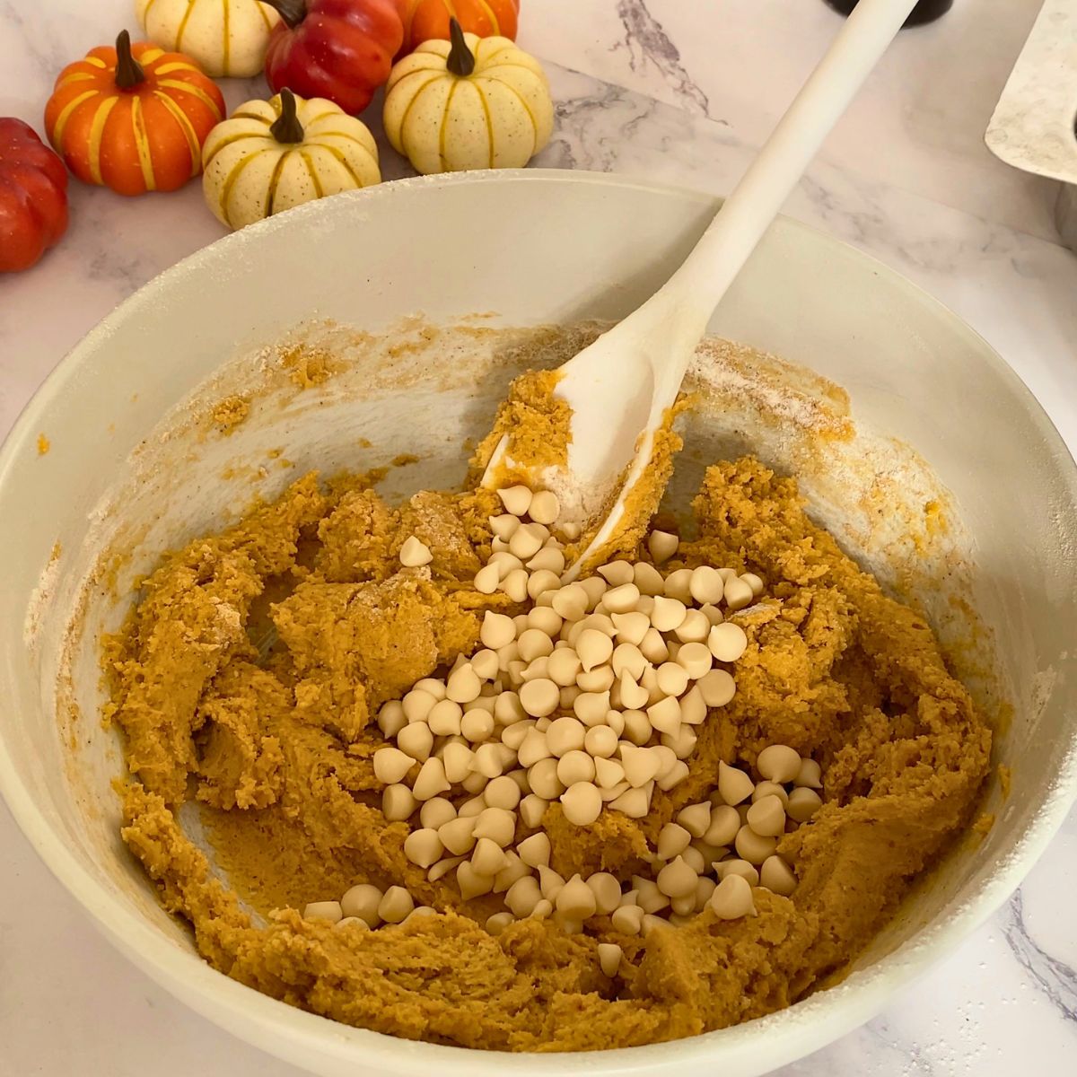 Adding chocolate chips to the pumpkin cookie dough.