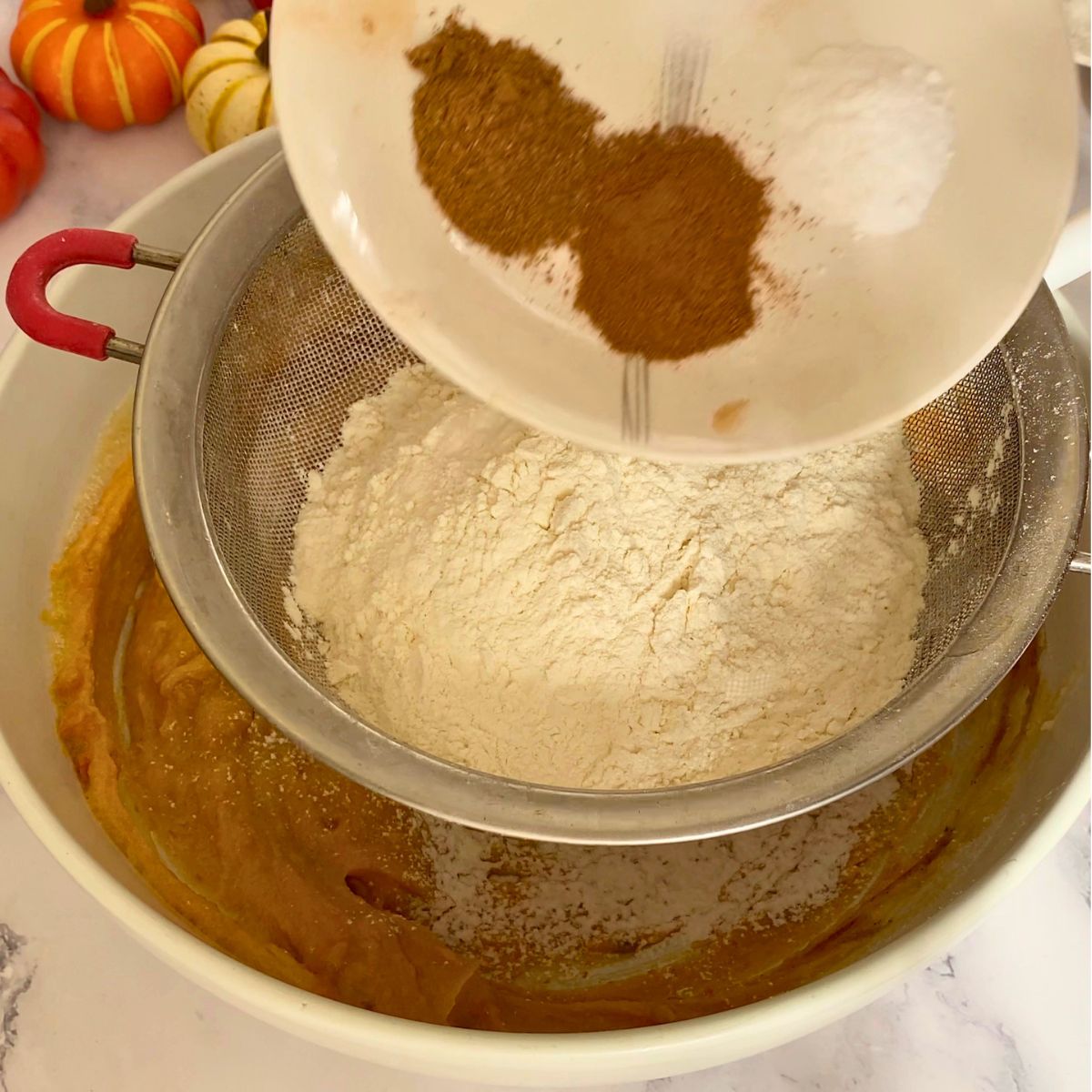 Adding flour and spices to pumpkin cookie dough.