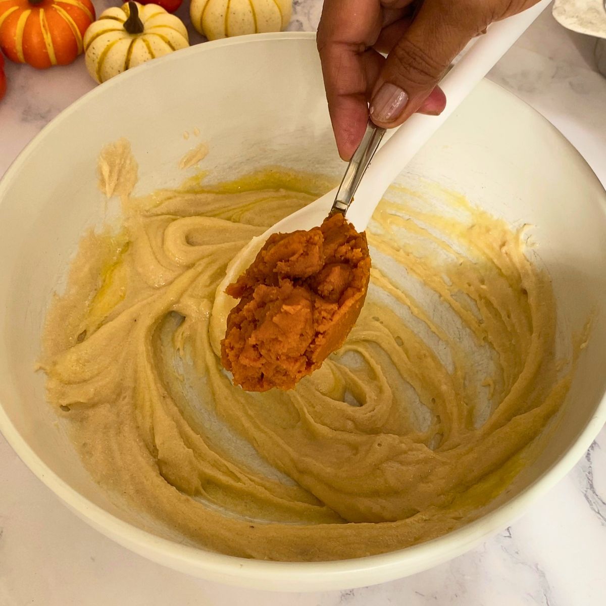 Adding pumpkin puree to the bowl.